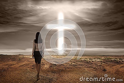 Back view asian woman walking to bright cross shape Stock Photo