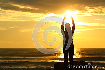 Woman reaching sun at sunset on the beach Stock Photo