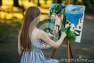 Back view of beautiful blond hair girl drawing a picture in the park Stock Photo