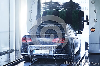 Back view of a carwash cleaning a car with rotating brushes Stock Photo