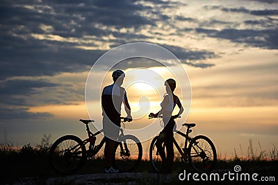 Back view of couple cyclists standing with bicycles and enjoying the sunset Stock Photo