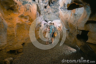 Back view. Couple of tourists exploring the cave. The interior of the cave. Touristic hiking route. Concept of excursions and Stock Photo