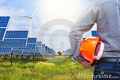 Back view engineer holding yellow helmet in solar station and wind turbines generating electricity Stock Photo