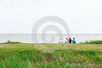 Back view of a family sitting on Minsmere beach in the UK Editorial Stock Photo