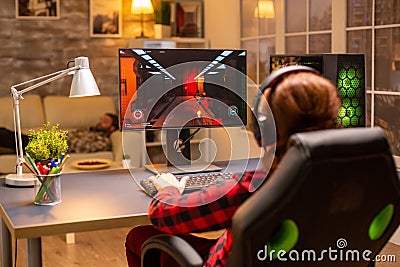 Back view of female gamer playing on powerful computer PC late at night in the living room Stock Photo