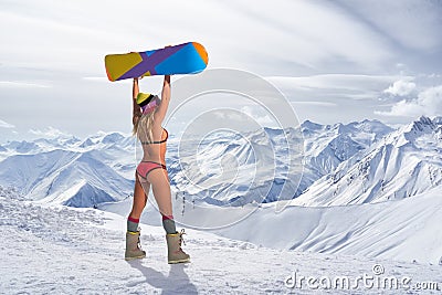 Back view of girl in bikini holding snowboard above head Stock Photo