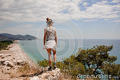 Back view girl in the light dress standing on the rock on the seacoast Stock Photo