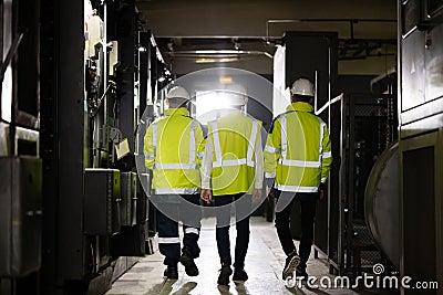 Back view of group multiethnic team of industrial engineers walking in manufacturing plant discussing new project or Stock Photo