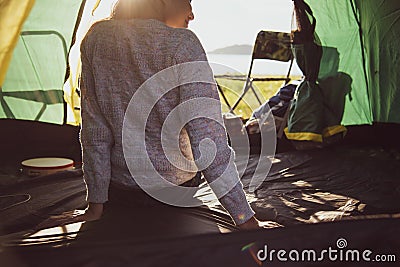 Back view of happy female tourist relaxing in camping tent with Stock Photo