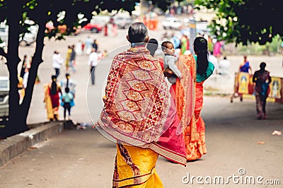 Back view of Indian female with colorful sari and lehenga walking toward the Hindu temple in India Editorial Stock Photo