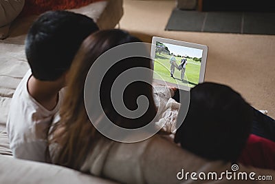 Back view of latin mother and children at home watching golf match on laptop Stock Photo