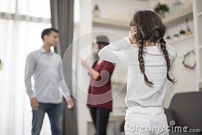 In back view, Little girl puts her hands on her ears because she does not want to hear her dad and mom quarrel. close ears, Family Stock Photo