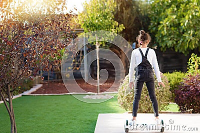 Back view of little girl riding a electric scooter outdoor. Young teenager balances on the Hoverboard. Stock Photo