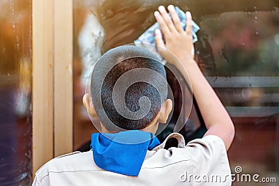 Back view of male student is helping to wipe the glass with wet newspaper at schoo Editorial Stock Photo