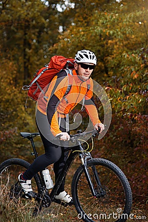 Back view of a man with a bicycle and red backpack against the blue sky. cyclist rides a bicycle. Stock Photo