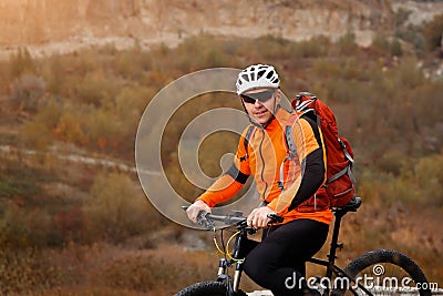 Back view of a man with a bicycle and red backpack against the blue sky. cyclist rides a bicycle. Stock Photo