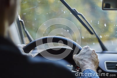 Back view of a man driving a car with moving windshield wipers during rain Stock Photo