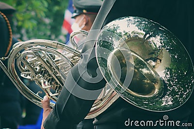 back view of a man in military uniform holding a French horn instrument Stock Photo