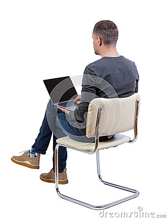 Back view of a man who sits on a chair with a laptop Stock Photo