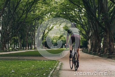 Back view of muscular cyclist in helmet biking at park Stock Photo