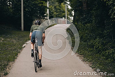 Back view of muscular man biking alone at green park Stock Photo