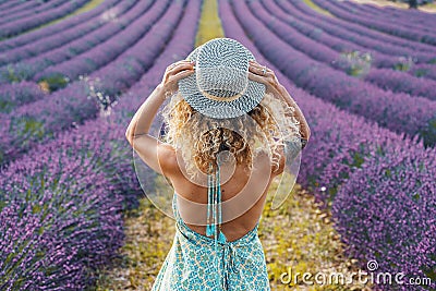 Back view of pretty tourist female agains a purple lavender field in europe travel scenic destination. Flowers fragrance and Stock Photo