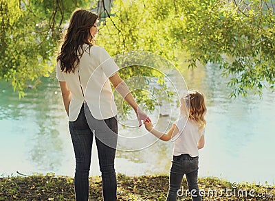 Back view silhouettes of mother and child together on lake in summer Stock Photo