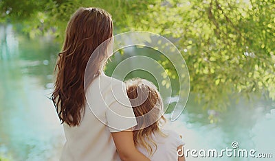 Back view silhouettes of mother and child together on lake in summer Stock Photo