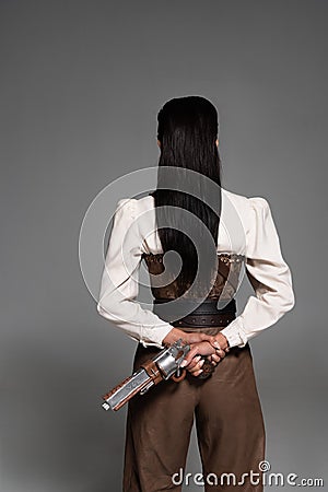 View of steampunk woman holding vintage pistol on grey Stock Photo