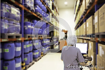 Back view of a stock keeper working on a desktop computer Aseptic products in the warehouse.shallow focus effect Stock Photo