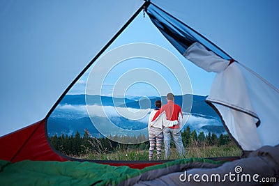 Back view of sweet pair standing hugging each other admiring the view of mountains Stock Photo