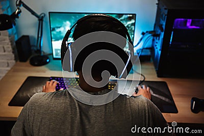 Back view of teenage gamer boy playing video games online on com Stock Photo