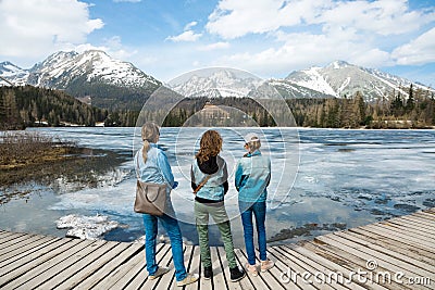 Back view on three female tourists staying by frozen mountain la Stock Photo