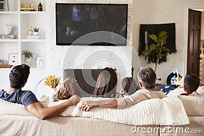 Back view of three generation Hispanic family sitting on the sofa watching TV Stock Photo