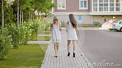 Two chicks in pretty summer outfits walk across the street