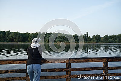 Back view of woman standing pier near lake Stock Photo