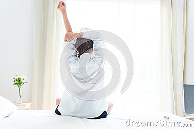 Back view of woman stretching in morning after waking up on bed Stock Photo