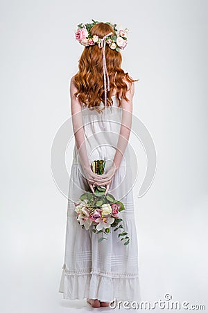 Back view of woman in wreath standing and hiding bouquet Stock Photo