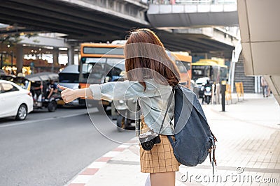 Back view of young Asian travel girl hitchhiking on the road in city. Life is a journey concept Stock Photo