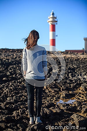 Back view of young beautiful woman enjoying lighthouse Stock Photo