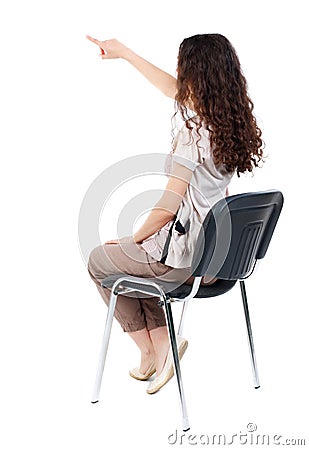 Back view of young beautiful woman sitting on chair and pointin Stock Photo