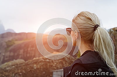 Back view of young blonde girl in mountains at sunset. Stock Photo