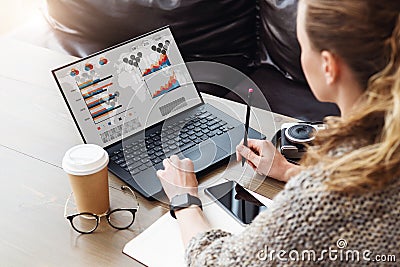 Back view. Young businesswoman sitting in office working on laptop computer with graphs, charts, diagrams on monitor Stock Photo