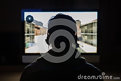 Back view of Handsome young gamer playing FPS video games at home in dark room. Stock Photo