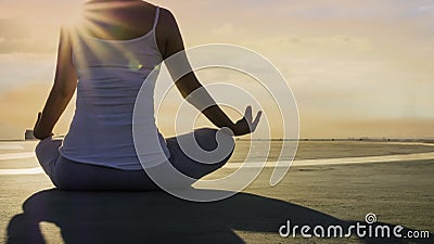 Back view young woman hand meditation lotus pose in sunlight mood on the rooftop building and evening sky scene Stock Photo