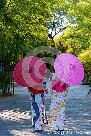 Back view of a young woman wearing a Japanese Yukata and holding a paper umbrella Stock Photo