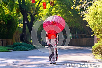 Back view of a young woman wearing a Japanese Yukata and holding a paper umbrella Stock Photo
