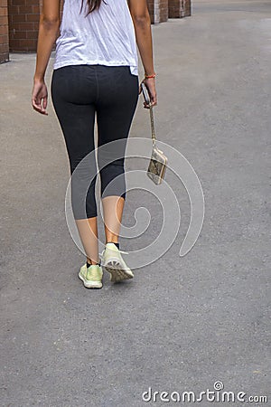 Back of a woman walking holding a hanging pocketbook in yoga pan Stock Photo