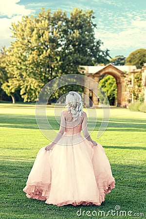 Back of woman wearing evening dress walking in formal garden Stock Photo