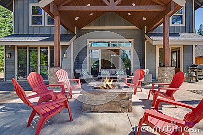 Back yard with fire pit and red chairs near newly bild luxury real estate home with forest biew and green grass Stock Photo